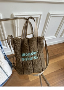 Detailed view of the blue Wonder Natural embroidery on the brown fleece tote bag
