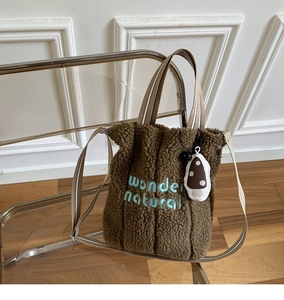Detail of caramel faux shearling tote bag with blue wonder natural embroidery and strap