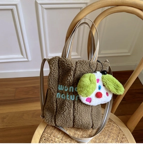 Detail of brown teddy fleece tote bag with blue 'wonder nature' embroidery and puppy charm