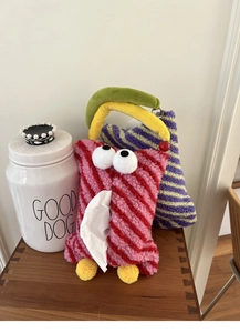 Detail of red and pink striped plush monster tissue bag with funny 3D eyes for car