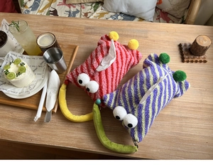 Close-up of cute monster plush car tissue boxes in red and purple striped faux fur