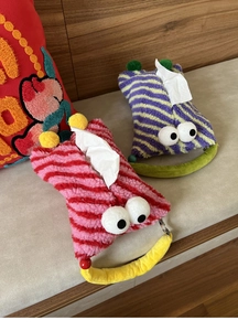 Close-up of cute plush monster tissue box holders with big eyes and colorful pom-poms