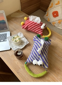 Close-up of monster plush tissue holders in striped velvet with 3D eyes and banana handles