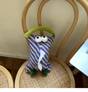 Detailed view of plush purple and yellow striped tissue box with 3D eyes and green handle