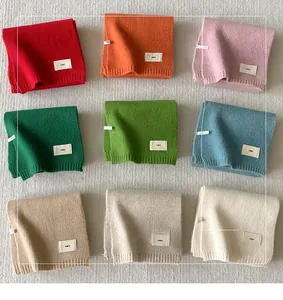 Detail showing nine colors of thick knitted scarves with white eno brand labels