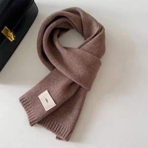 Thick knitted brown winter scarf with a minimalist brand label on a soft fabric