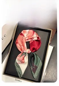 Gros plan d'un foulard en soie rose corail à fleurs montrant éclat satiné et bordures