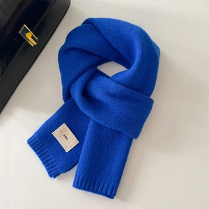 Dettaglio della sciarpa in maglia blu Klein con etichetta tessuta bianca emo