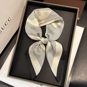 Elegant black and white geometric silk scarf displayed on a luxury decorative tray