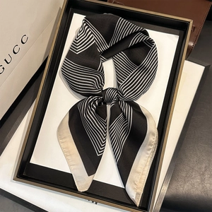 Elegant black and white striped silk scarf tied in a bow on a luxury minimalist backdrop