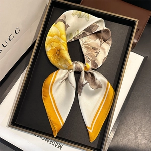 Détail d'un foulard en soie à fleurs présentant d'élégants motifs floraux jaunes et bruns