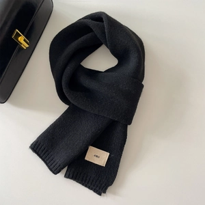 Thick black knitted winter scarf featuring a woven emo patch on a solid textured fabric