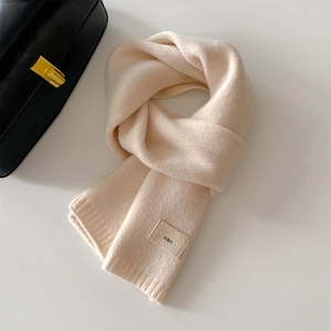 Minimalist cream knit scarf with square logo tag shown against a white background
