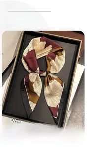 Close-up of burgundy floral silk square scarf folded in a black presentation tray