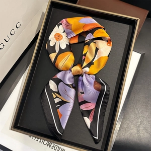 Elegant floral silk scarf with lilac and orange patterns on a premium display tray