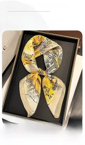 Detail of silk-like scarf with yellow house print tied in an elegant bow shape