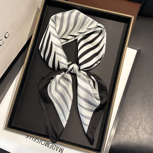 Elegant black and white striped silk-like scarf neatly displayed on a luxury tray