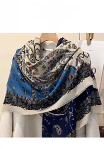Detail view of navy paisley shawl with tassels draped over a white wool coat on a hanger