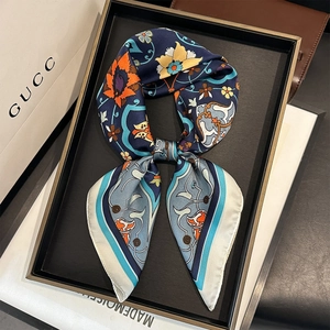 Detailed view of dark blue silk scarf with floral patterns displayed as a premium gift