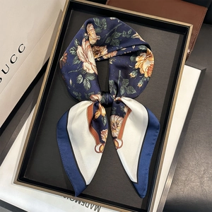 Detail of navy silk scarf with floral and equestrian patterns in a luxury gift box