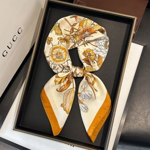 Floral print silk scarf with butterfly pattern and yellow borders on display tray