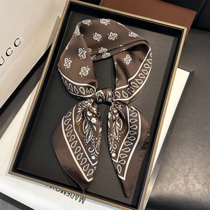 Élégant foulard en soie marron foncé avec motifs paisley noué en nœud sur plateau