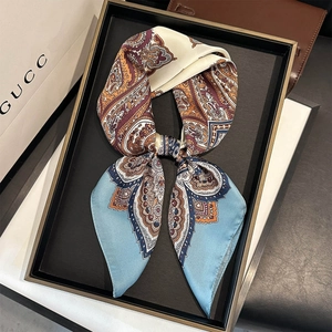 Détail d'un foulard en soie à imprimé cachemire noué en nœud sur un plateau noir