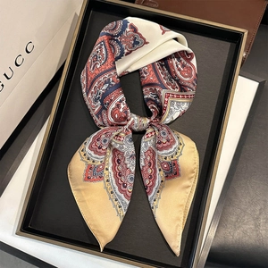 Détail d'un foulard en soie à motif paisley noué en boucle sur un plateau de luxe