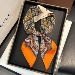 Carré de soie élégant à motif Paisley orange et doré, noué de manière stylée