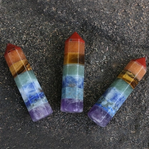 Set of three hexagonal 7 chakra natural crystal stone pillars on stone background