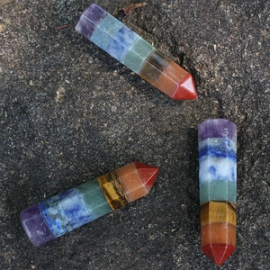 Natural 7 chakra crystal hexagonal prism pillars stones displayed on stone background