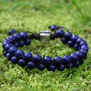 Double-layered braided bracelet with natural blue lapis lazuli beads on green moss
