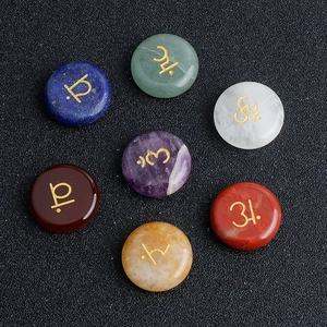 Polished 7 Chakra natural gemstones set with gold engraved yoga symbols on black surface
