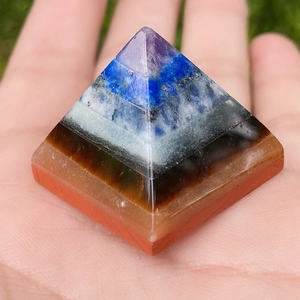 Natuurlijke kristallen piramide met amethist en tijgeroog vastgehouden in de hand