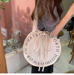 Close-up of circular canvas shoulder bag featuring an inspirational quote print