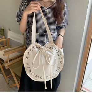 Detail of round canvas tote bag with drawstring closure and black aesthetic typography