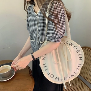 Detail of round canvas tote bag with circular text print and drawstring side knots
