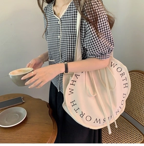 Detail of round canvas tote bag with artistic typography in a lifestyle setting