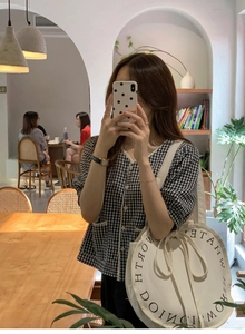 Detail of white circular canvas tote bag with black ring text on a summer casual outfit