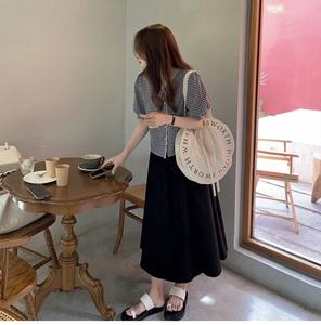 Lifestyle view of a round canvas shoulder bag styled with a minimalist Korean summer outfit
