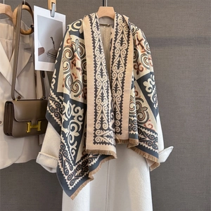 Detail view of ethnic geometric jacquard scarf with brown fringe on a white coat