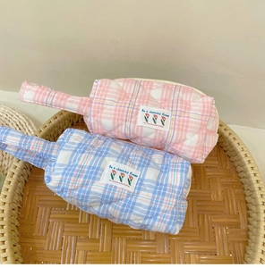 Detailed view of quilted cotton cosmetic bags in pink and blue with diamond stitching