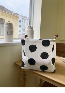 Close-up of canvas laundry basket with black polka dots and brown leather handles