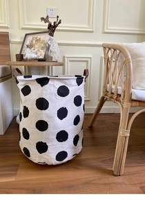 Close-up of canvas storage basket with black polka dots and brown leather handles