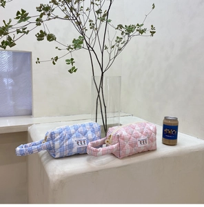 Detailed quilted texture and daisy zipper on candy-colored makeup bags in blue and pink