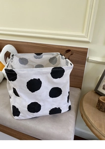 Close-up of fabric laundry basket with black polka dots and brown leather handles