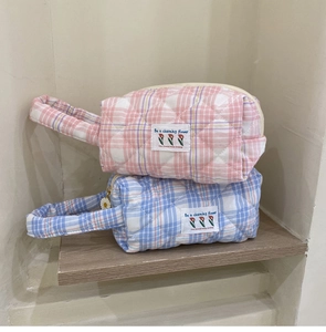 Detail of candy-colored quilted makeup bags with daisy zipper and woven labels