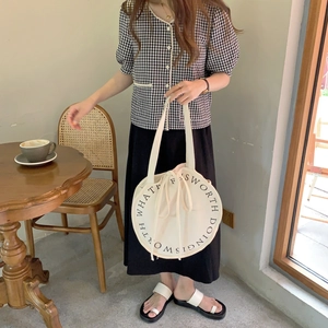 Minimalist white round canvas shoulder bag with typographic design for casual wear