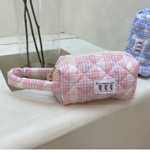 Detail of pink quilted plaid handbag with daisy zipper charm and tulip patch label