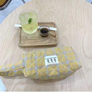 Detailed close-up of a yellow quilted plaid makeup bag with a charming flower label